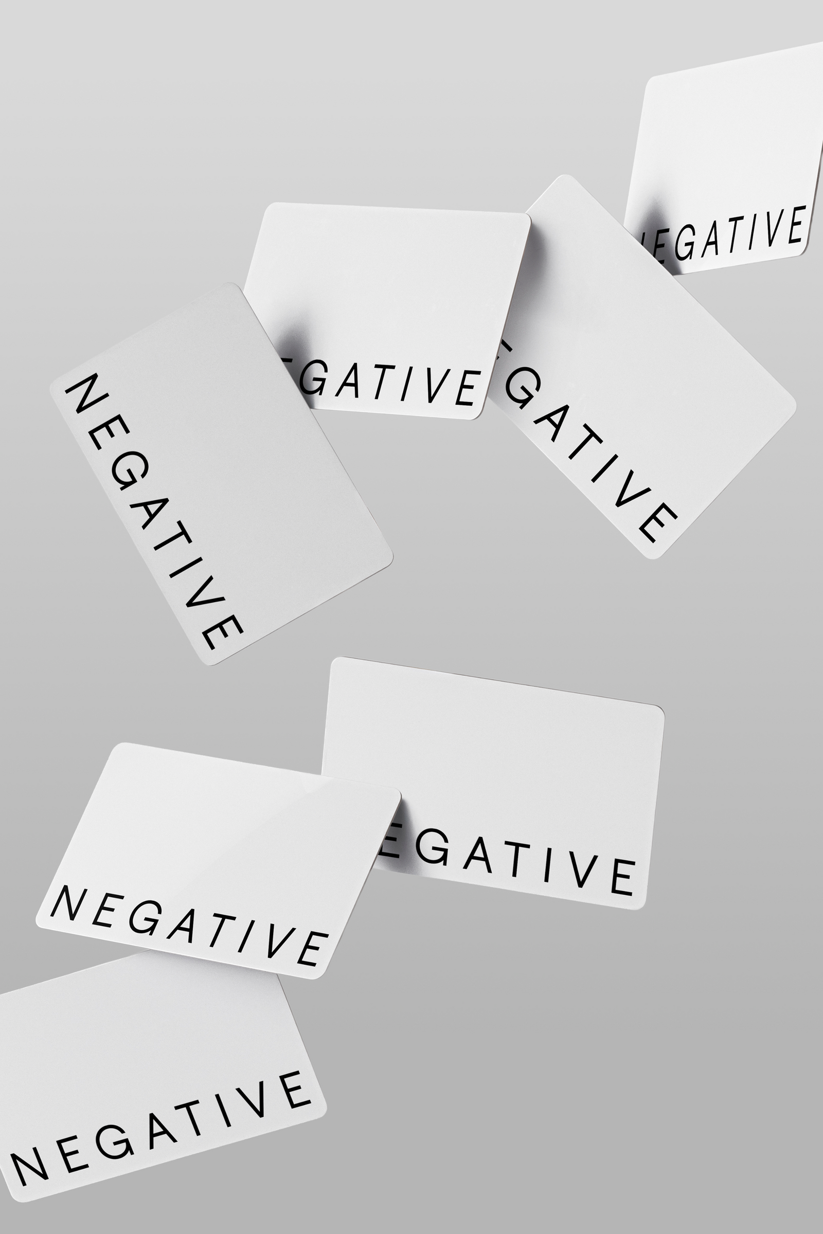 Set of white gift cards with 'NEGATIVE' text, angled and overlapping