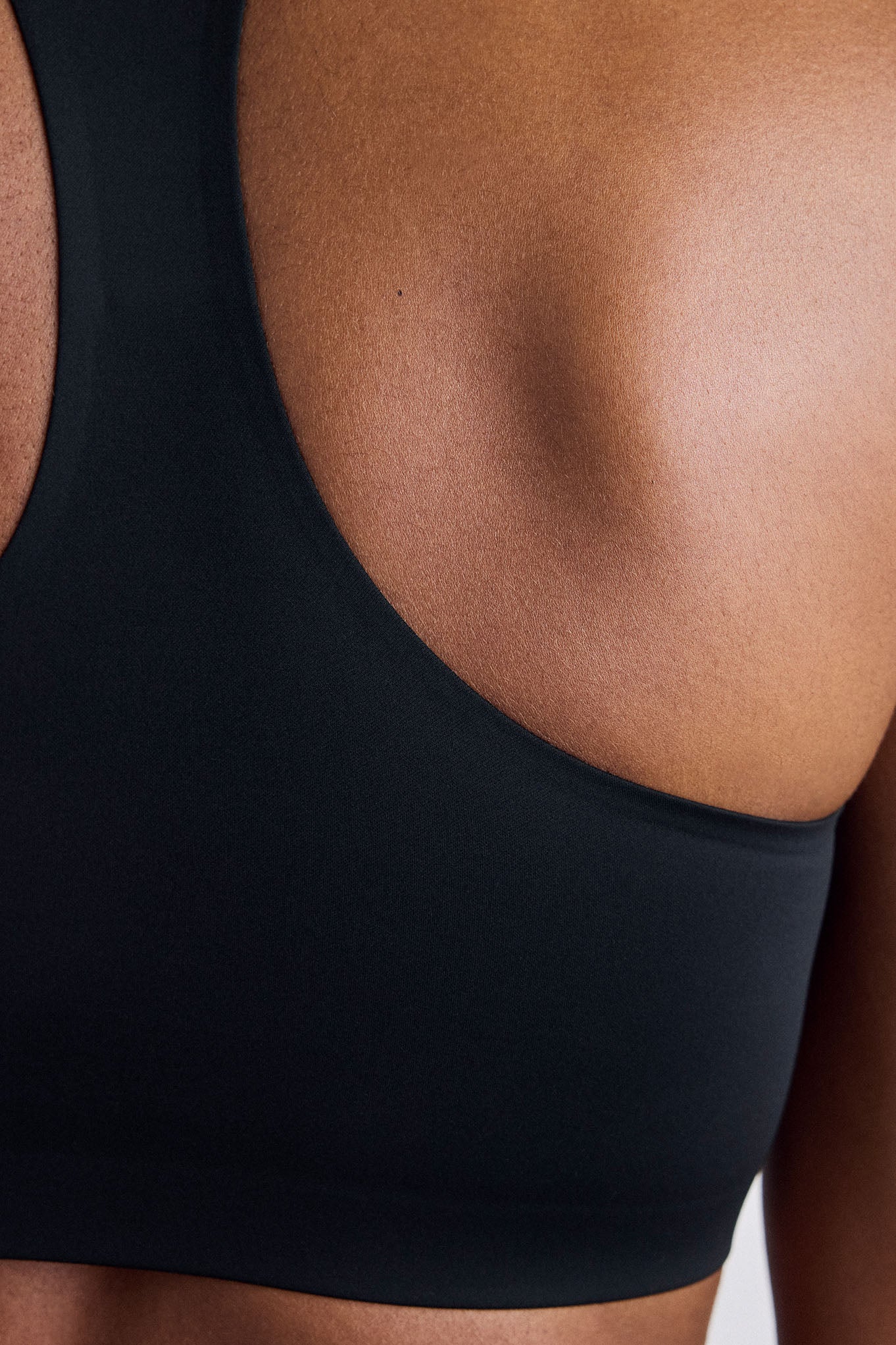 Close-up of a person wearing a black sports bra, showing the back and upper back area.
